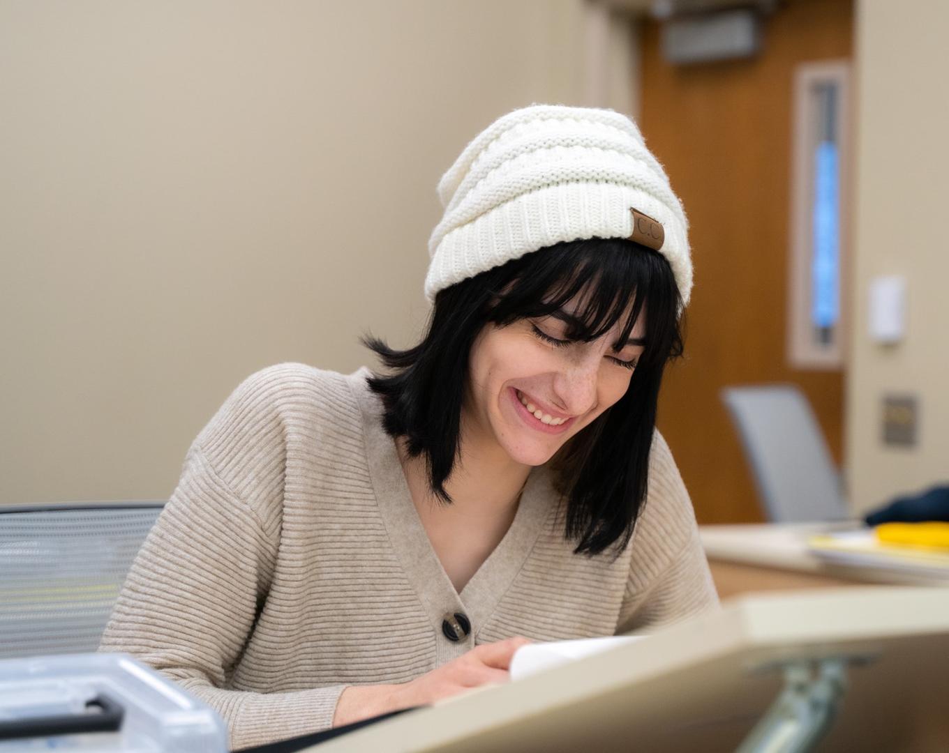 Student wearing a beanie is working on a project.